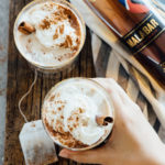 Two mugs of chai tea latte next to a bottle of Malabar.