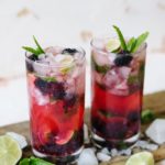 Two Malabar Spiced Blackberry Mojitos with slices of lime garnished with mint.