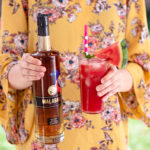 Woman holding a Watermelon Malabar Mojito and a bottle of Malabar Spiced Liqueur