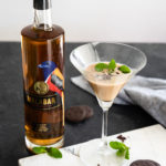 A Malabar Spiced Liqueur cocktail that tastes like the famous Girl Scout Cookie in a glass next to a bottle of malabar on a tray.