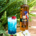 A Blue Havaiyee Next To A Bottle Of Malabar Spiced Liqueur